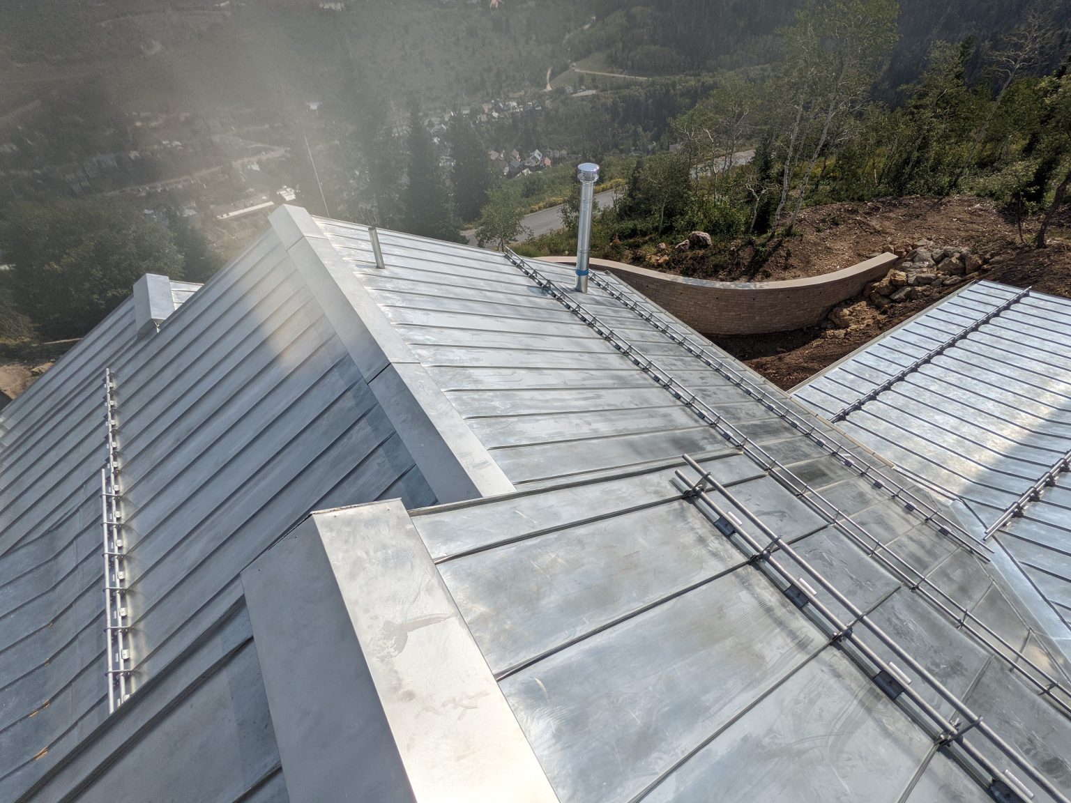 A sheet metal roof on a large building overlooking a forested valley.