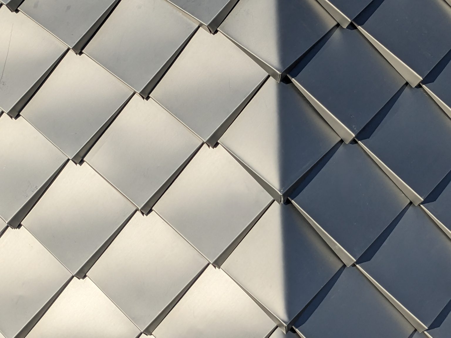 A close-up of repeating, overlapping pattern of diamond-shaped metal shingles.