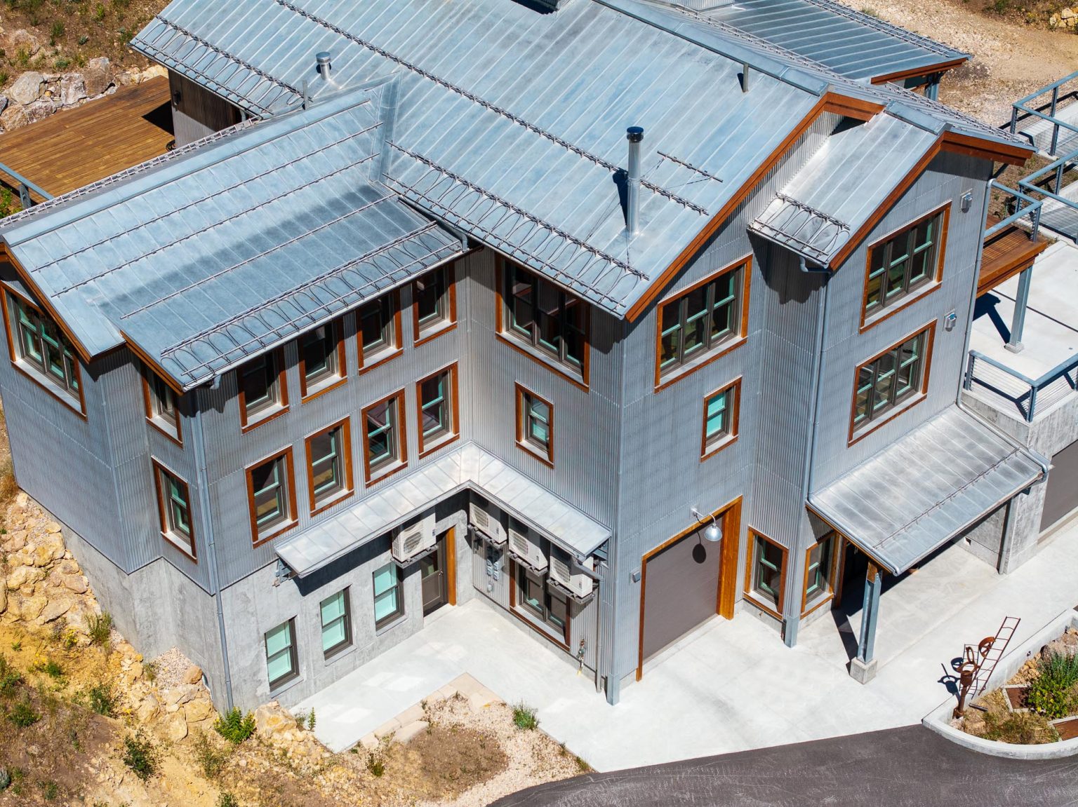 An aerial view of a large 3 story building with a sloped tin metal roof.